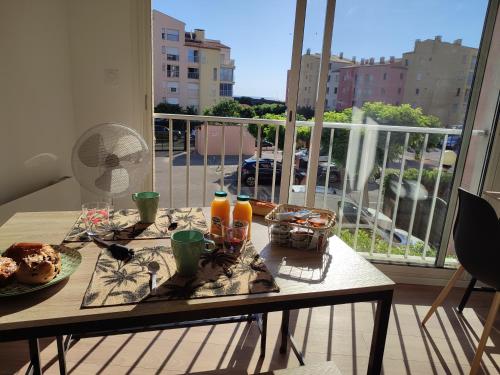 une table avec de la nourriture et des boissons sur un balcon dans l'établissement STUDIO COSY, au Cap d'Agde