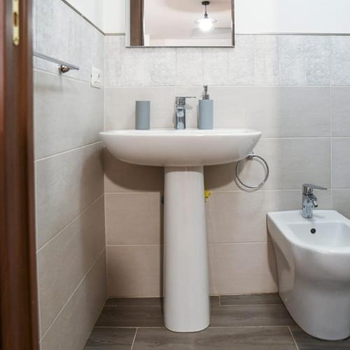 La salle de bains est pourvue d'un lavabo blanc et de toilettes. dans l'établissement A Villeggiatura, à Scilla