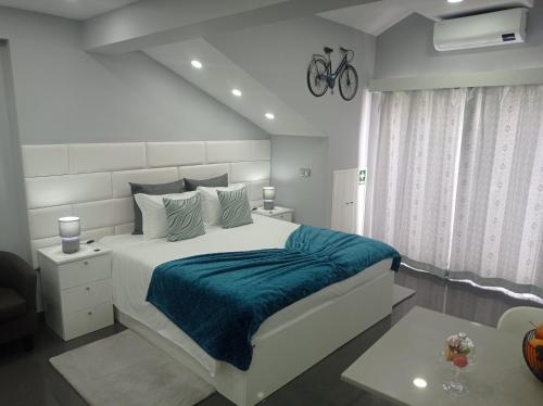 um quarto branco com uma cama grande e um cobertor azul em Casa Rua Velha em Horta