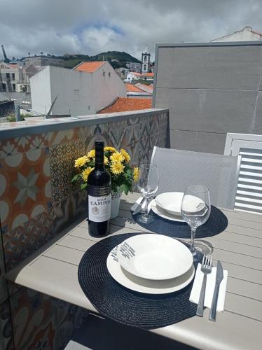 a table with a bottle of wine and glasses on a balcony at Casa Rua Velha in Horta