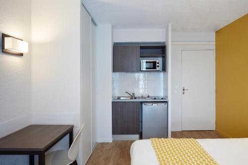 a small room with a bed and a kitchen at Aparthotel Adagio Access Poitiers in Poitiers