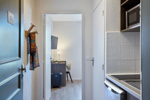 a door leading into a room with a kitchen at Aparthotel Adagio Access Poitiers in Poitiers