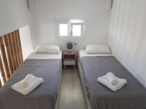 two beds in a small room with towels on them at Empyreal Blue Apartments in Dexamenes