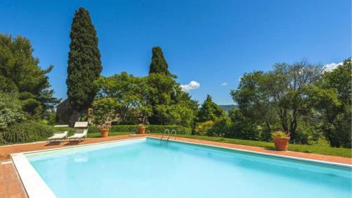 a swimming pool with two chairs and trees at Podere contignano in Contignano