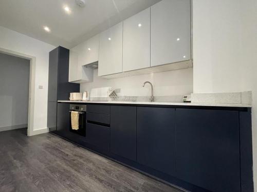 a kitchen with white cabinets and a black counter top at Star London Finchley Road 3-Bed Retreat in London