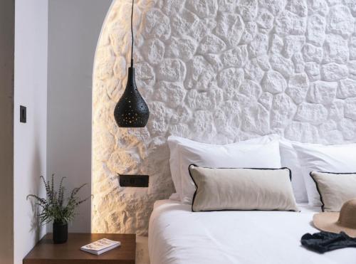 a bedroom with a white bed with a stone wall at Kedros Katikies in Kalamaki Heraklion