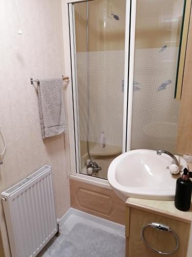 a bathroom with a white sink and a shower at Ezüst fenyő vendégház in Borzont
