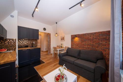 a living room with a couch and a brick wall at Maya's Flats & Resorts 47 - Dluga 18/19 in Gdańsk