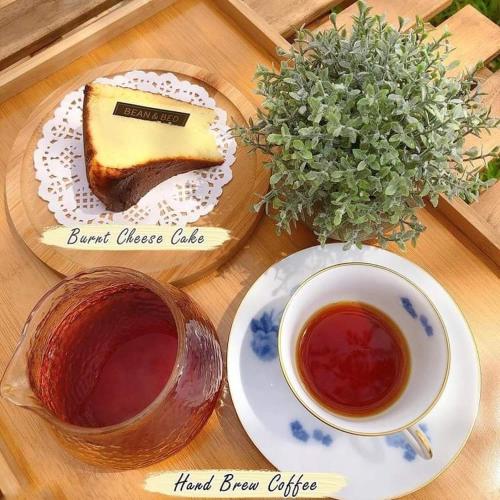 a table with a piece of cake and a cup of tea at Bean & Bed Guesthouse in Muar
