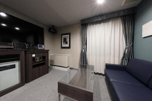 ein Wohnzimmer mit einem blauen Sofa und einem TV in der Unterkunft ホテルバースデー岐阜西店 HOTEL Birthday GifuWest in Gifu