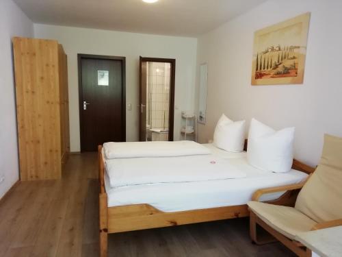 a bedroom with a large bed and a chair at Hotel Hanseatic-garni in Wuppertal