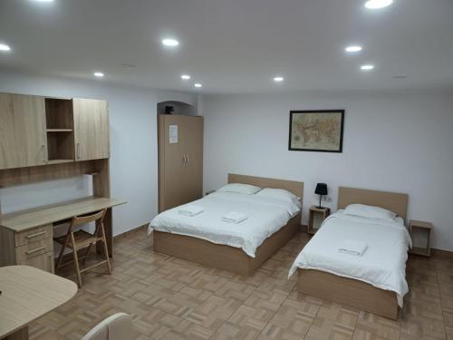 a room with two beds and a desk and a table at Casa Rezidentiala Aria in Cluj-Napoca