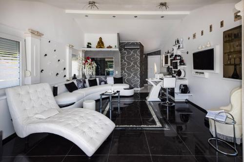 uma sala de estar com um sofá branco e cadeiras em Apartment OM em Povlja