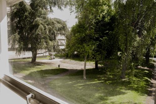 una finestra con vista su un cortile alberato di Belle appartement lumineux -Tram au pied de l'immeuble - a Hérouville-Saint-Clair