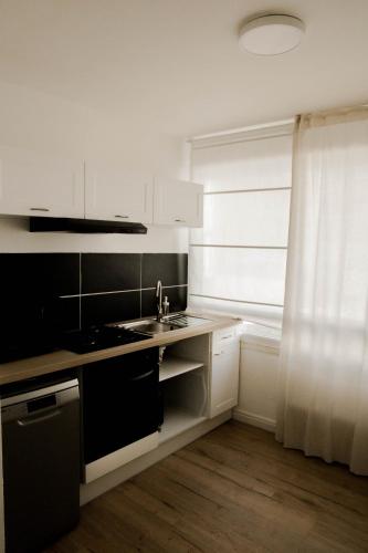 una cucina bianca con lavandino e finestra di Belle appartement lumineux -Tram au pied de l'immeuble - a Hérouville-Saint-Clair
