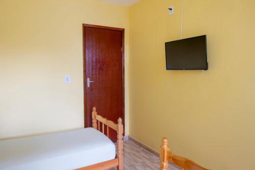a bedroom with a bed and a television on the wall at OYO Pousada Simone in Itaboraí