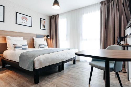 a bedroom with a bed and a desk and a table at Appart'City Collection Saint Germain en Laye in Saint-Germain-en-Laye