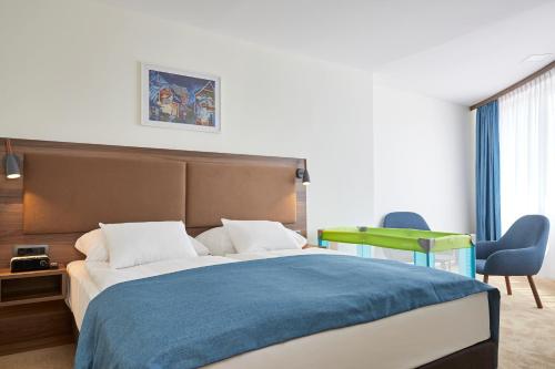 a bedroom with a large bed with a blue blanket at THERMAL RESORT LENDAVA - Terme Lendava, Hotel in Lendava