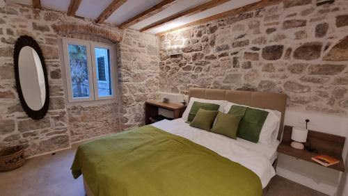 a bedroom with a bed and a stone wall at Vitelli Apartments and Rooms in Split