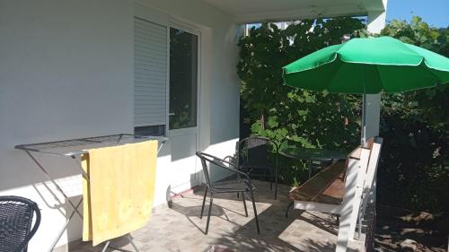 a patio with a table and a green umbrella at Sea Cottage Studios in Budva