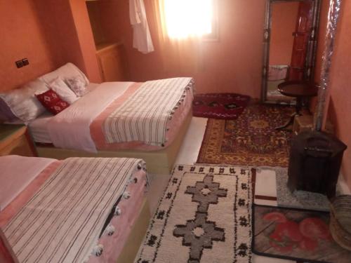 a room with two beds and two rugs at Auberge des lacs in Imilchil