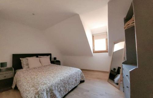 a white bedroom with a bed and a window at Gîte Emeraude in Bergheim