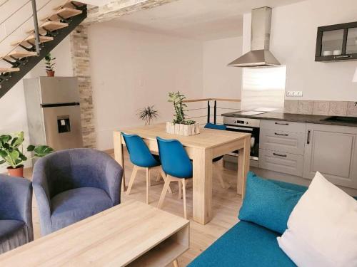 uma cozinha com uma mesa de madeira e cadeiras azuis em Gîte Emeraude em Bergheim