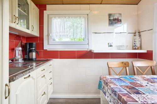 una cocina con armarios blancos y azulejos rojos y blancos en Tide, en Simonsberg
