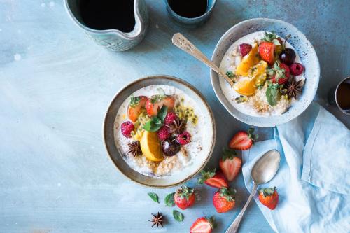 two bowls of oatmeal with fruit and strawberries on a table at Hotel Aisi in Batumi
