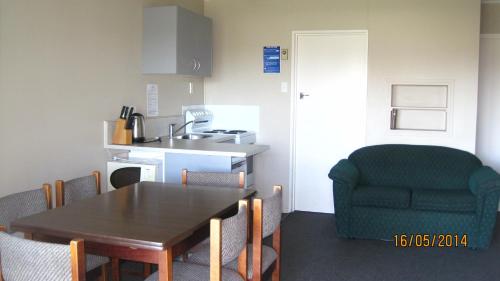 a kitchen with a dining room table and a green chair at High Country Lodge, Motels & Backpackers in Twizel