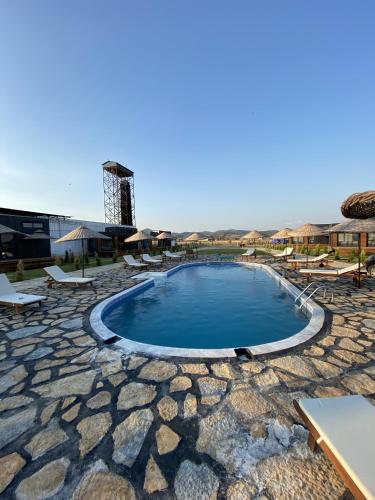 a swimming pool with chairs and a building in the background at Lavira Tiny House Village in Bogazici