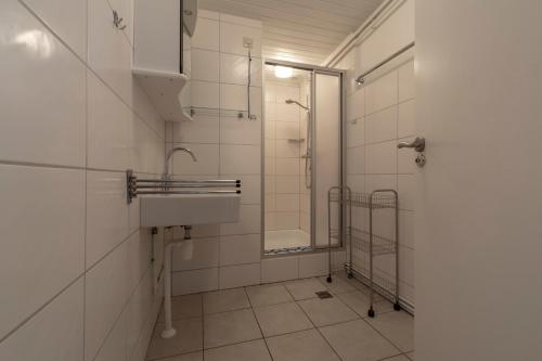 een witte badkamer met een wastafel en een douche bij Duinland 90 Sint Maartenszee in Sint Maartenszee