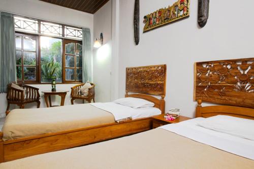 a bedroom with two beds and a table and a window at Agung And Sue Watering Hole I in Sanur