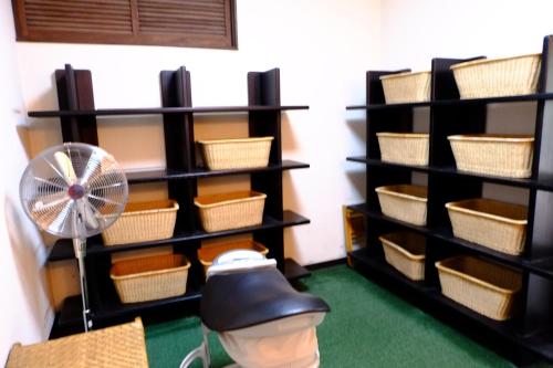a room with shelves with baskets and a fan at Asumi Onsen in Fujiyoshida