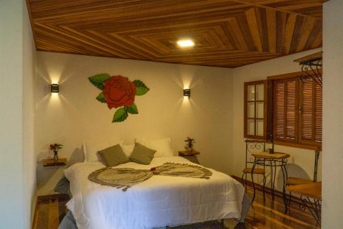 a bedroom with a bed with a flower on the wall at Montanhas Do Visconde in Visconde De Maua