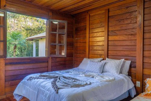 a bed in a wooden room with a window at Montanhas Do Visconde in Visconde De Maua