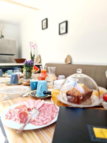 La Dame de Coeur Deauville, Touques Maison d'hôtes-B&B في توكويز: طاولة خشبية عليها أطباق طعام