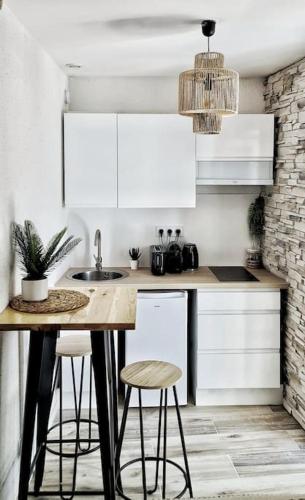 une cuisine avec des armoires blanches et une table avec des tabourets dans l'établissement #NEW#TERRASSE SUD OUEST#PIED DE LA CITÉ #1, à Carcassonne