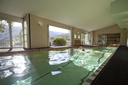 a person swimming in an indoor swimming pool at Novotel Lake Crackenback Resort in Crackenback