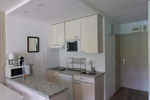 a kitchen with white cabinets and a sink and a microwave at Tignes Joli Studio avec vue imprenable sur le lac in Tignes