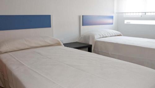 een kamer met twee bedden en een tafel erin bij Apartamentos Boutique Benicasim in Benicàssim