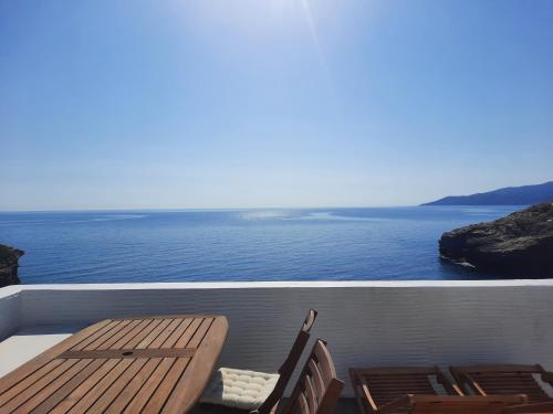 a deck with a table and chairs and the ocean at Vitali Beach Houses in Andros