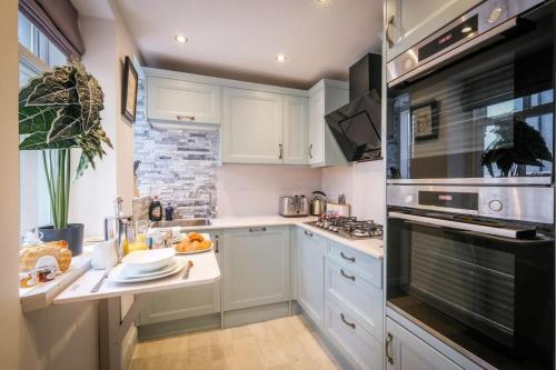 a kitchen with white cabinets and a stove top oven at Glen Wynne Apartment Lovely Central Pet Friendly - FREE off-site Health Club access with Pool, Sauna, Steam Room & Gym in Windermere