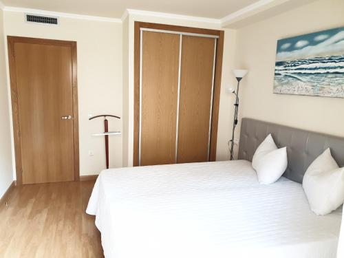 a bedroom with a white bed and a wooden floor at Apartamento Residencial Carmen in Oropesa del Mar