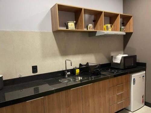 a kitchen with a sink and a microwave at Globo Lar Studios in Limeira