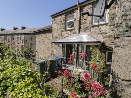 a stone house with a fence and flowers at 4A Victoria Place in Barmouth