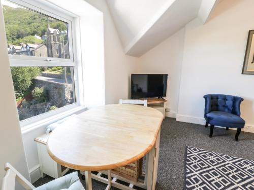 a dining room with a wooden table and a large window at 4A Victoria Place in Barmouth