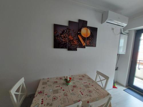 een eetkamer met een tafel en wat foto's aan de muur bij Topaz Central Apartment in Bacău