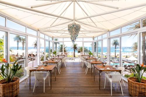 a patio area with tables, chairs and umbrellas at The Bay Hotel in Cape Town