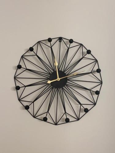 a black clock hanging on a white wall at Citadela in Primošten